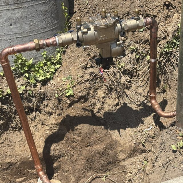 New copper piping and brass backflow preventer installed at a residential property