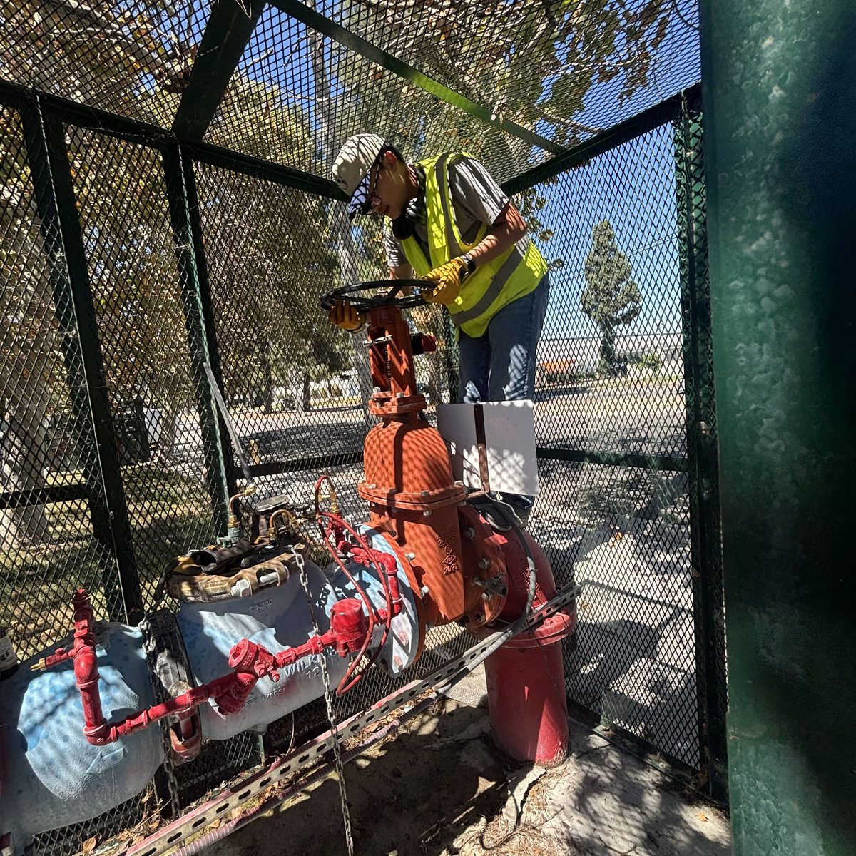 Certified tester running a test on a caged commercial fire service backflow assembly