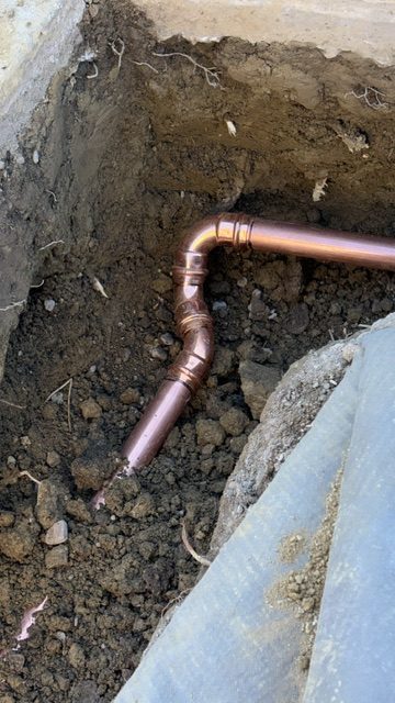 Repaired copper water line exposed in an open excavation