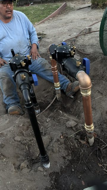 Technician installing large control valves in an open excavation